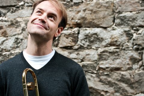 Shawn Grocott mit Posaune vor einer Mauer